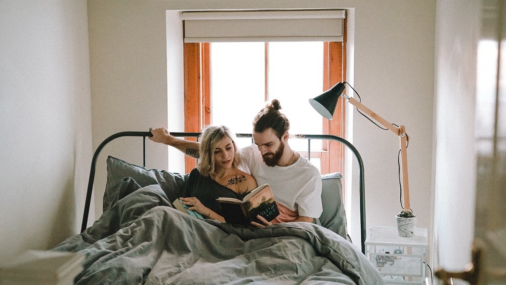 Ein junges Paar liegt im Bett und liest gemeinsam ein Buch